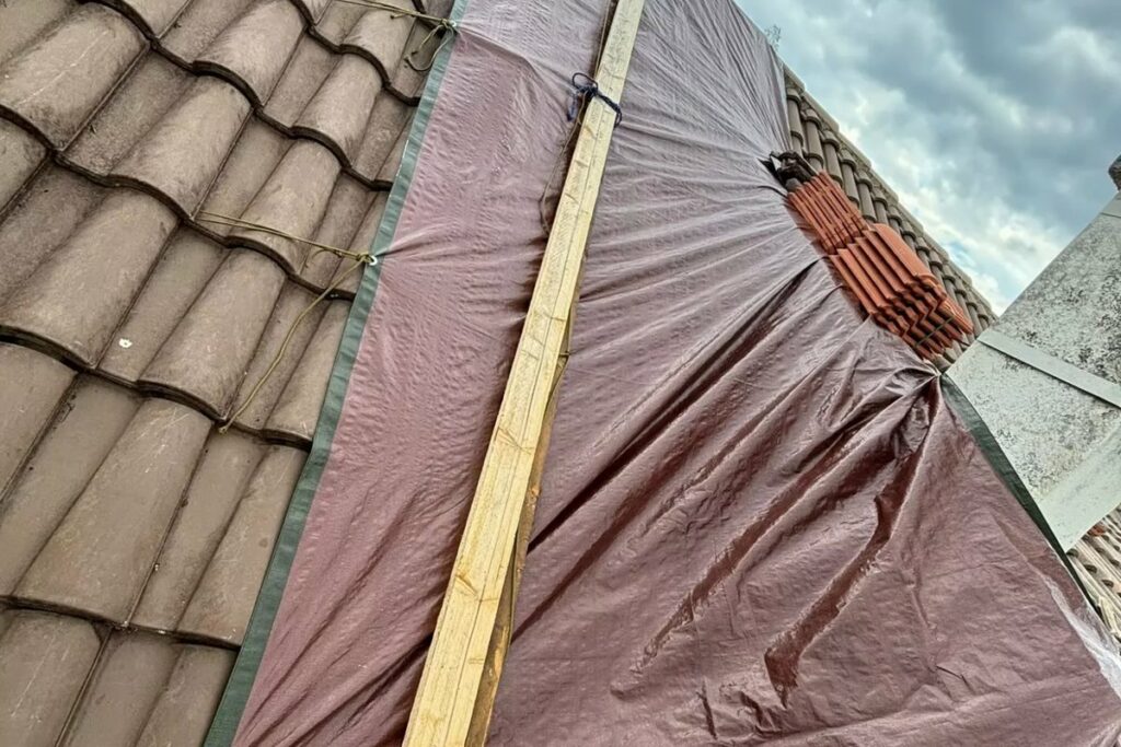 Bâche posée sur une toiture en tuiles pour une mise hors d'eau en urgence
