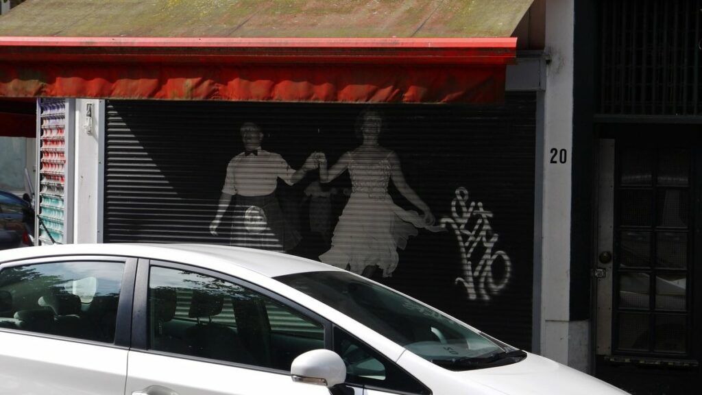 Devanture de commerce fermée par un rideau métallique décoré d'une fresque